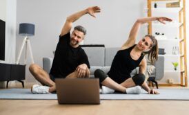 a couple practicing yoga poses in front of a laptop during a 15-minute morning workout session