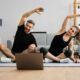 a couple practicing yoga poses in front of a laptop during a 15-minute morning workout session