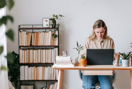 a woman working at a desk with a laptop, focused on freelance strategy consulting tasks