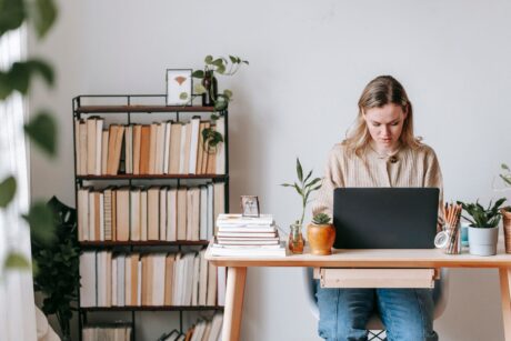 a woman working at a desk with a laptop, focused on freelance strategy consulting tasks