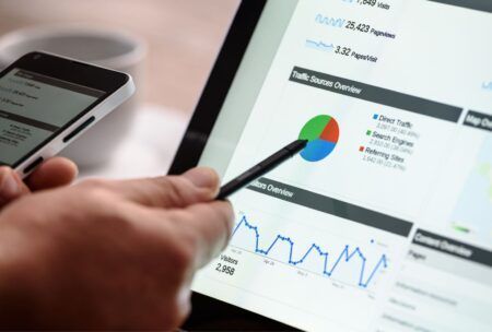 A man multitasking on a laptop and smartphone, analyzing website analytics using Google AdWords Business