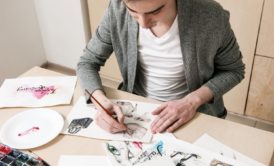 a man focused on his art at a table, learning how to become a freelance artist