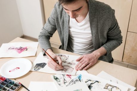 a man focused on his art at a table, learning how to become a freelance artist