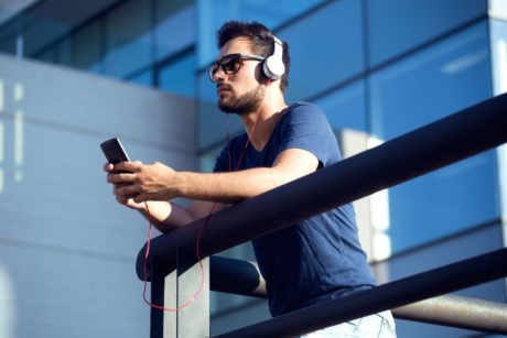 a man with headphones, focused on his cellphone, enjoying a satb composition in a serene environment