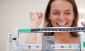 a woman holds a weight scale, symbolizing her journey in a weight loss course