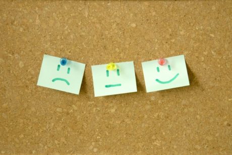 three cheerful sticky notes with smiley faces are pinned to a cork board, illustrating the concept of master your emotions