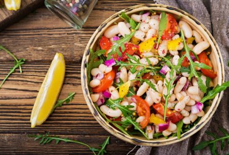 a vibrant bowl of beans and assorted vegetables on a wooden table, ideal for a nutritious diet and meal planning
