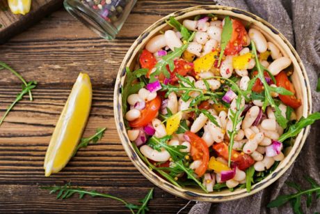 a vibrant bowl of beans and assorted vegetables on a wooden table, ideal for a nutritious diet and meal planning