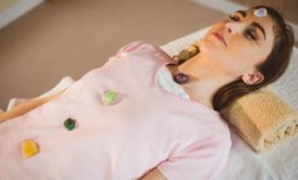 A woman on a bed with a crystal ball, participating in a crystal therapy healing course