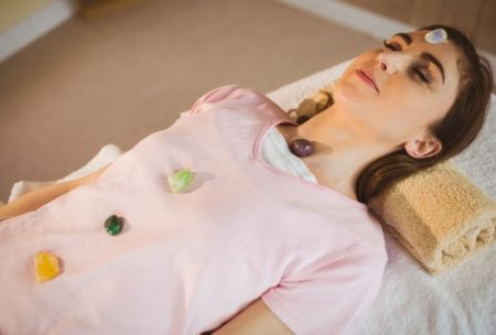 A woman on a bed with a crystal ball, participating in a crystal therapy healing course