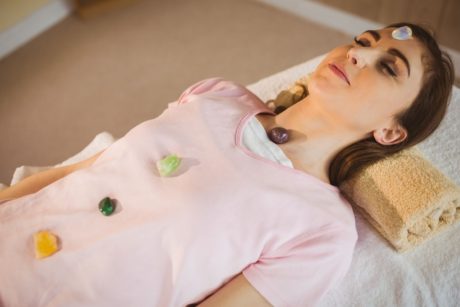 A woman on a bed with a crystal ball, participating in a crystal therapy healing course