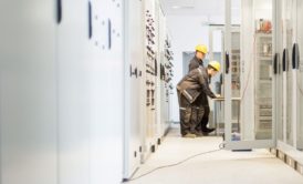 Two men working in a large room with electrical equipment in an Air Insulated Electrical Substation Design