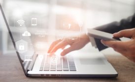 man typing on laptop and holding smartphone