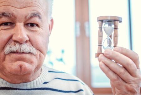 old man holding small hourglass