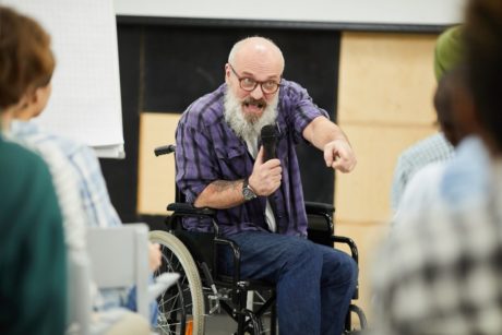 man in wheelchair presenting to a crowd