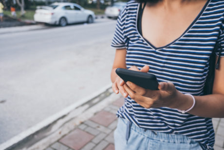 a woman in a striped shirt holds a cell phone, focused on how to learn candlestick patterns for trading