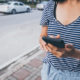 a woman in a striped shirt holds a cell phone, focused on how to learn candlestick patterns for trading