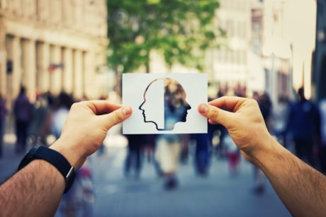 a person displays a paper cutout of a head, symbolizing emotional intelligence coaching and self-awareness development