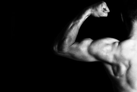 A man flexes his muscles in a striking black and white image, showcasing impressive muscle growth and hypertrophy