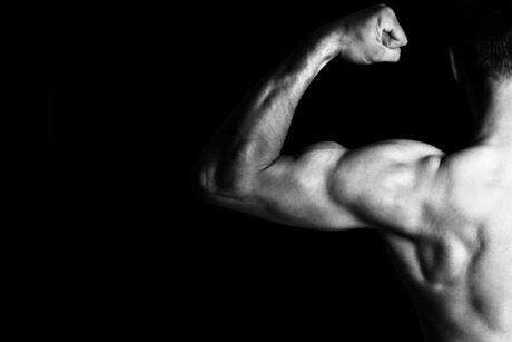 A man flexes his muscles in a striking black and white image, showcasing impressive muscle growth and hypertrophy