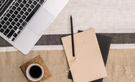 a laptop, notebook, and two cups of coffee on a table, symbolizing a freelance writing course environment
