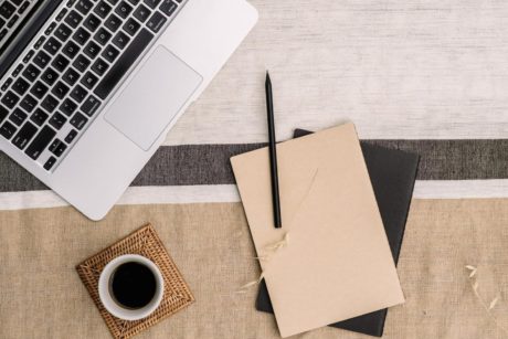 a laptop, notebook, and two cups of coffee on a table, symbolizing a freelance writing course environment