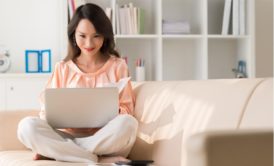 woman sitting on couch typing in laptop