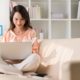 woman sitting on couch typing in laptop