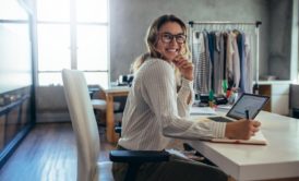 a woman with glasses at a desk uses a laptop, concentrating on her Amazon wholesale selling business