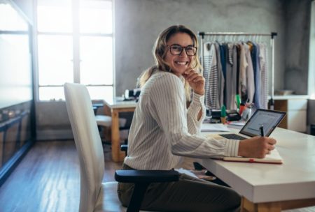 a woman with glasses at a desk uses a laptop, concentrating on her Amazon wholesale selling business