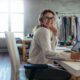 a woman with glasses at a desk uses a laptop, concentrating on her Amazon wholesale selling business