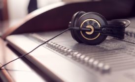 a pair of headphones rests on a mixing board, symbolizing the essentials of music production 101