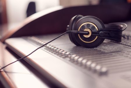 a pair of headphones rests on a mixing board, symbolizing the essentials of music production 101