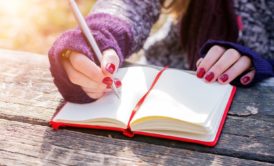 woman writing on red notebook