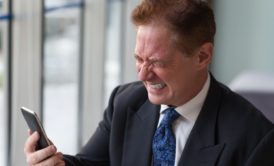 a businessman in suit checking phone, likely participating in online anger management course