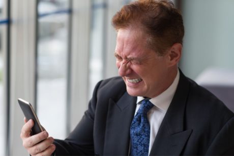 a businessman in suit checking phone, likely participating in online anger management course