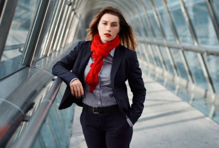 A professional woman wearing a business suit and red scarf, demonstrating body language fundamentals