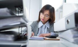 A professional woman in a business suit diligently works on paperwork during a QuickBooks training course