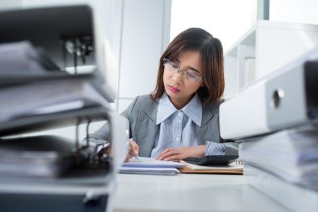 A professional woman in a business suit diligently works on paperwork during a QuickBooks training course