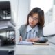 A professional woman in a business suit diligently works on paperwork during a QuickBooks training course