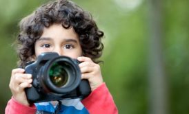 young boy with a camera, learning about photography for kids by taking a picture