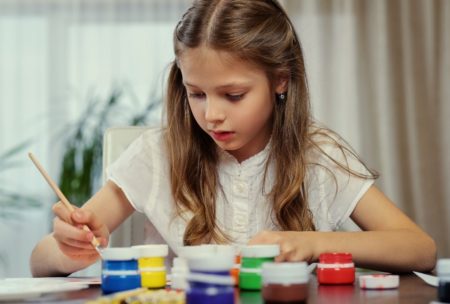 young girl happily painting with colorful acrylics on her hands at an acrylic painting workshop