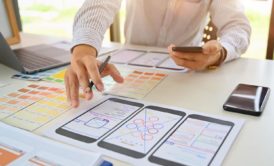 a man designing a mobile app on a smartphone and laptop, learning how to become a ux designer