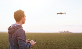 In a field, a man with beginner aerial videography skills controls a drone, capturing mesmerizing footage