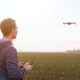 In a field, a man with beginner aerial videography skills controls a drone, capturing mesmerizing footage