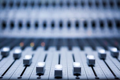close-up of a mixing board with numerous knobs, used for composing ambient music in a creative studio setting