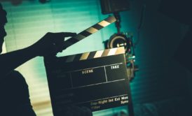 a person holds a clapper board in front of a camera, symbolizing a video production course in action