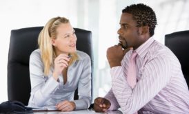 A man and woman engage in a discussion at an office table, focusing on conflict management with emotional intelligence
