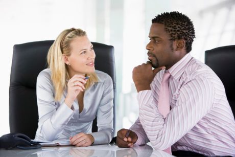 A man and woman engage in a discussion at an office table, focusing on conflict management with emotional intelligence