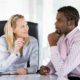 A man and woman engage in a discussion at an office table, focusing on conflict management with emotional intelligence